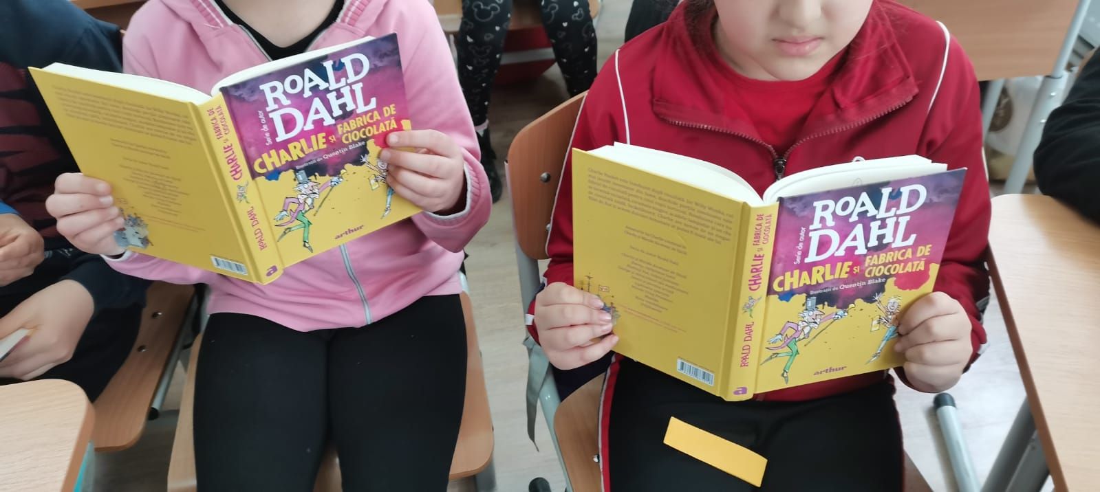 Doi elevi citind „Charlie și fabrica de ciocolată” de Roald Dahl