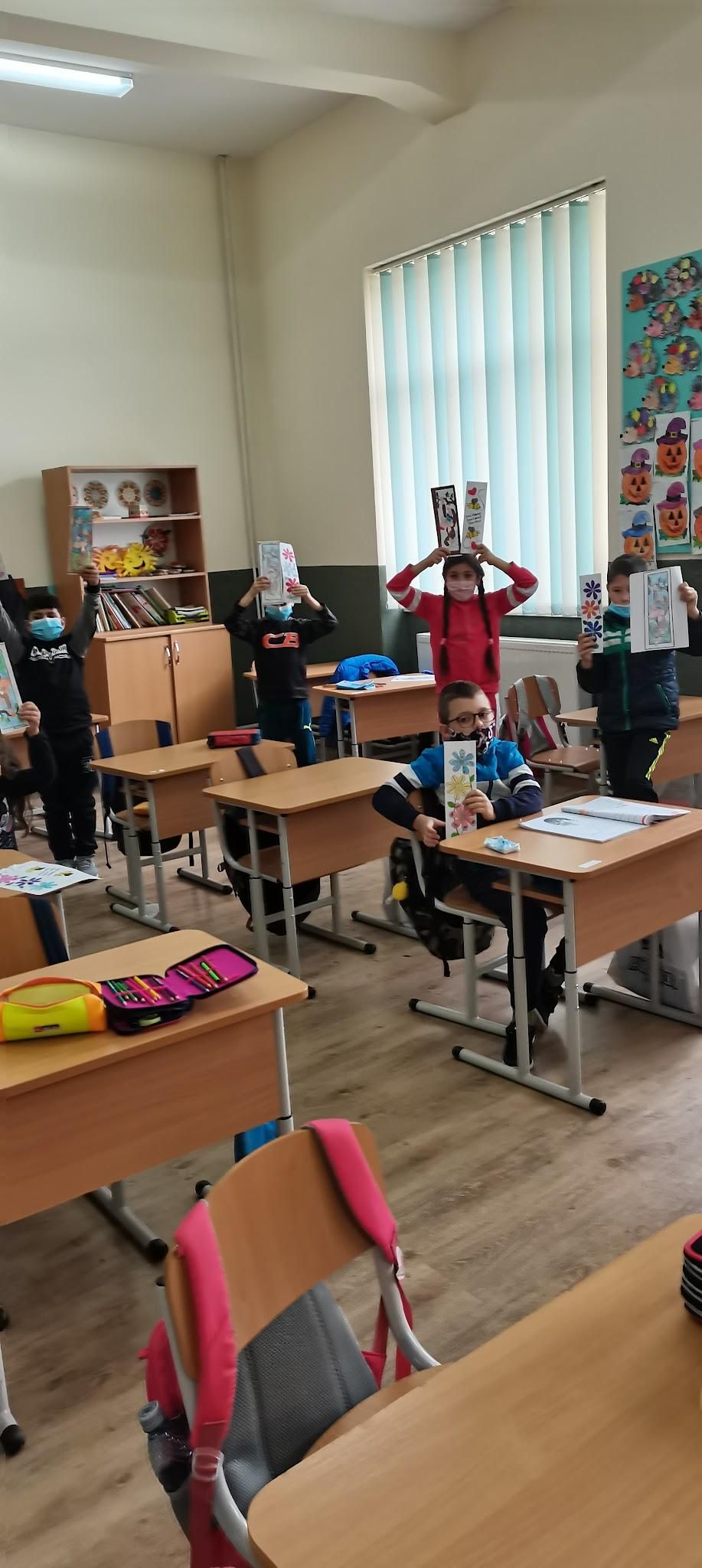 Elevi în bănci care își ridică cărțile și fișele