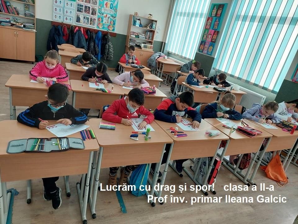 Elevi din clasa a II-a desenând în bănci, cu inscripția „Lucrăm cu drag și spor!”