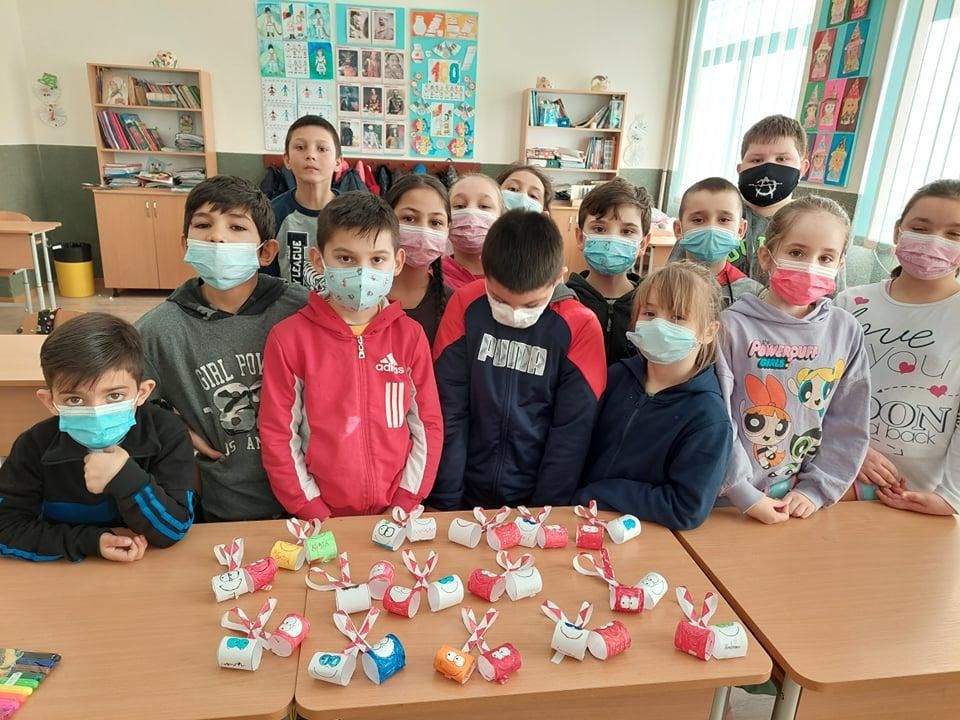 Elevi în spatele unei mese pe care sunt mărțișoarele lucrate de ei
